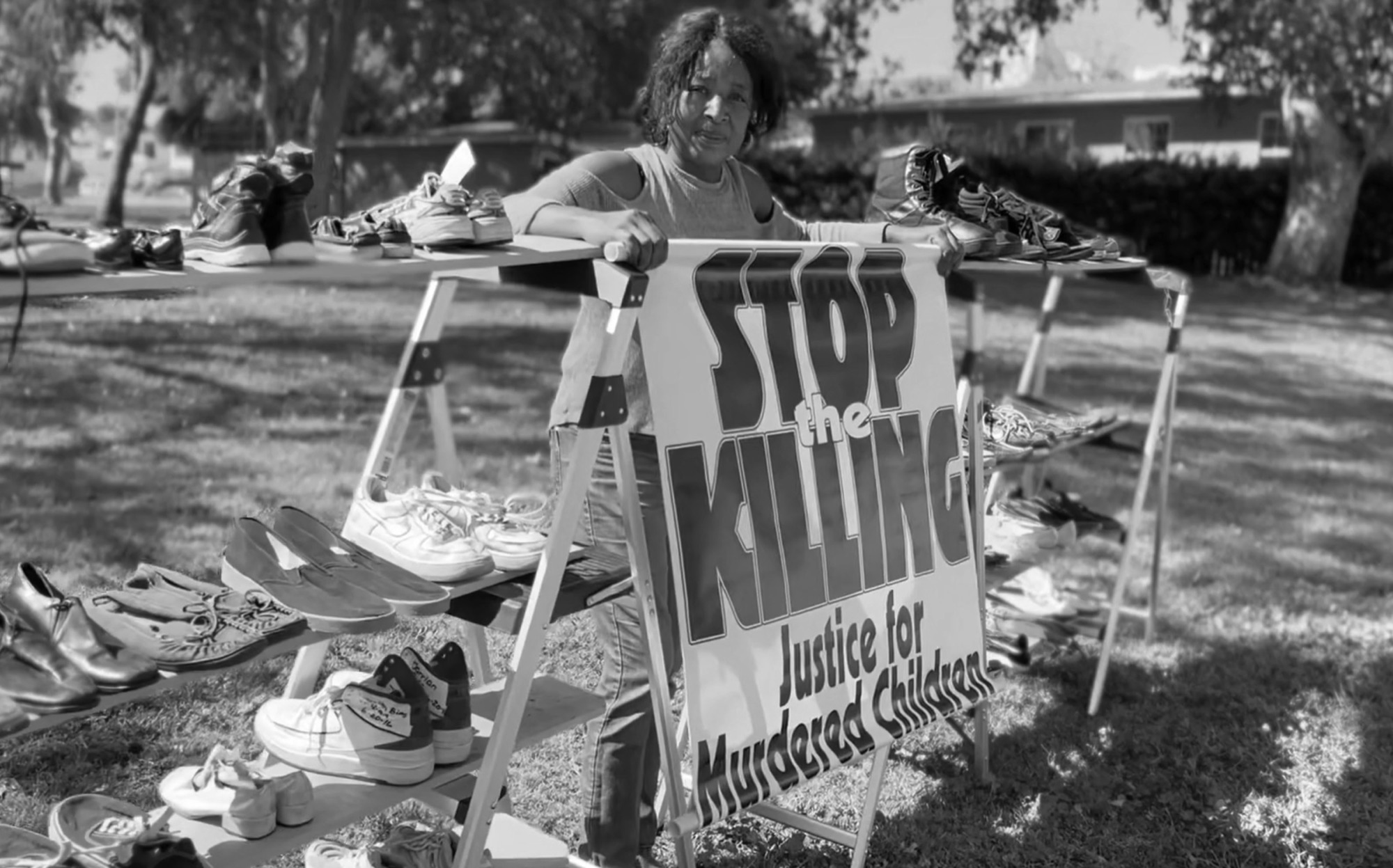 LaWanda Hawkins of Justice for Murdered Children, beside tables of shoes left for children lost to violence