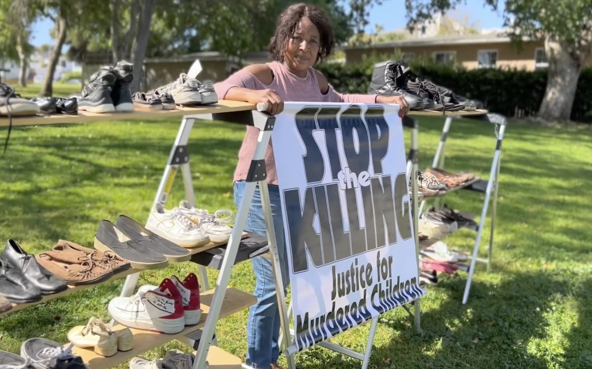 Lawanda Hawkins of Justice for Murdered Children, beside tables of shoes left for children lost to violence