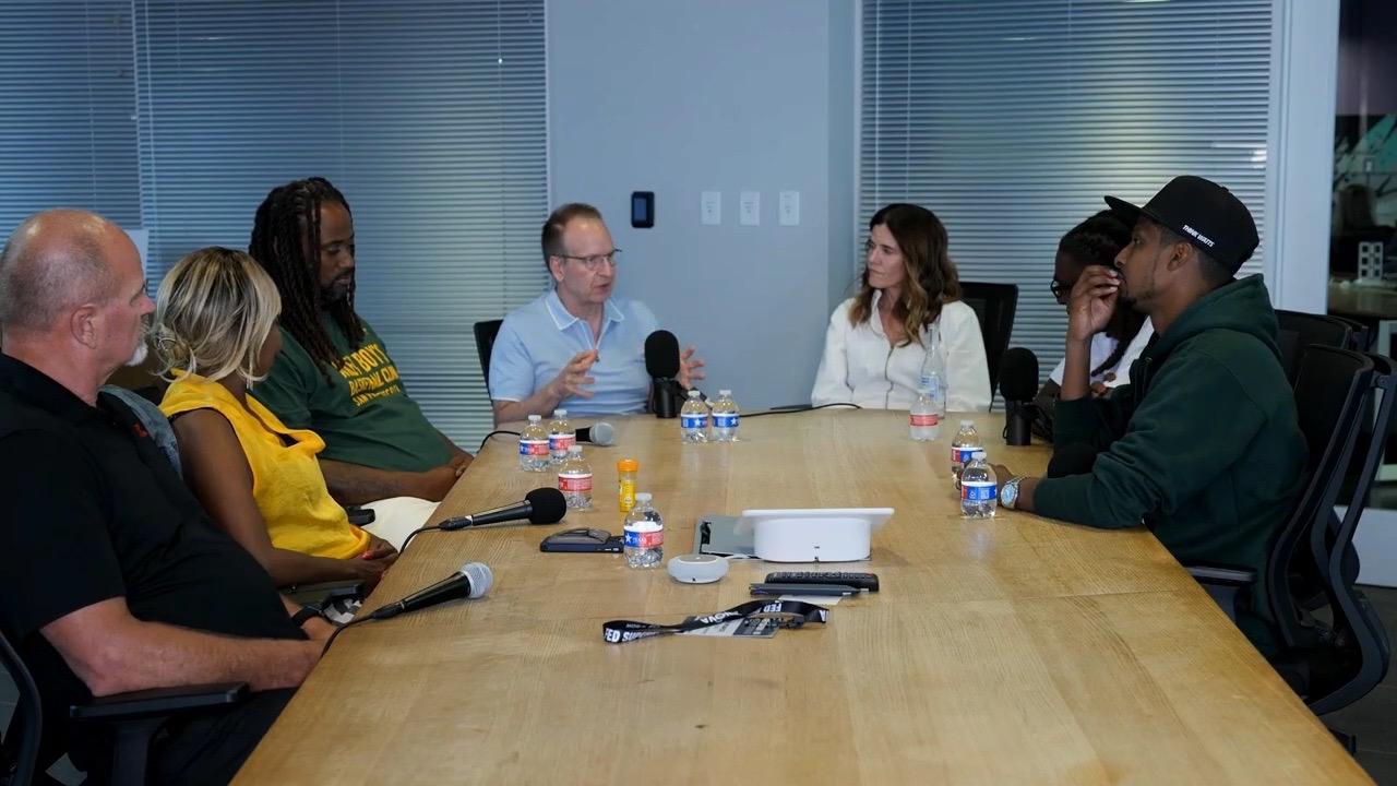 Filmmakers and host in conversation around a conference table on the let’s go there set