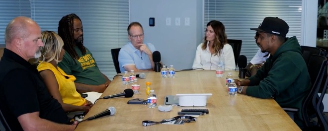 Filmmakers and host in conversation around a conference table on the let’s go there set
