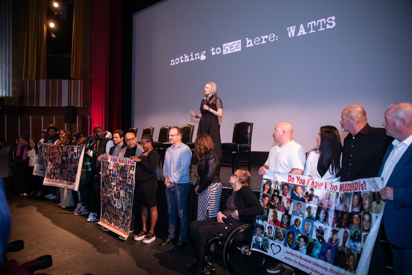 Filmmakers on stage at Coolidge Corner holding a banner of faces, the title on the screen behind them